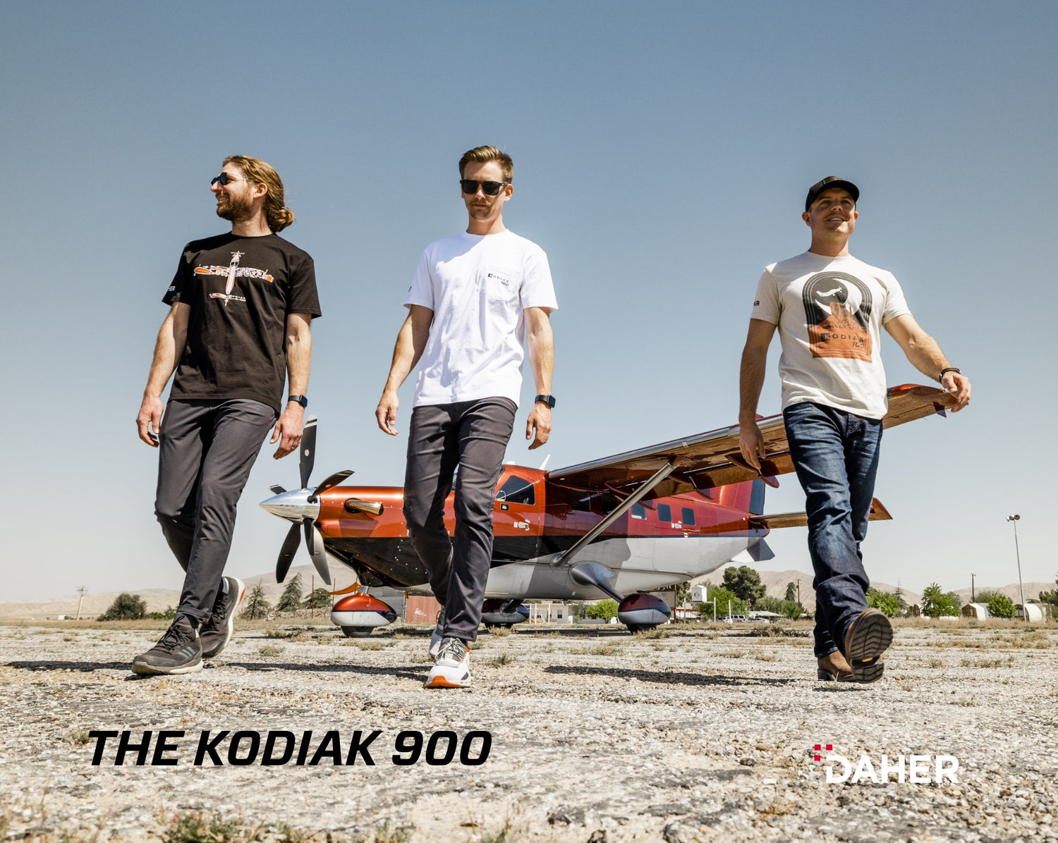 Three guys standing in front of a Kodiak 900 plane.