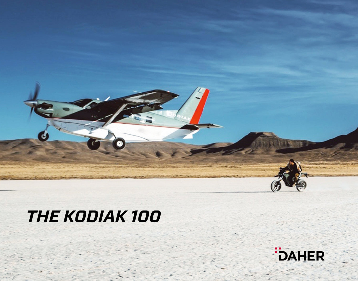 The tbm 960 taking off in the sky and then a man riding a bike to the side.